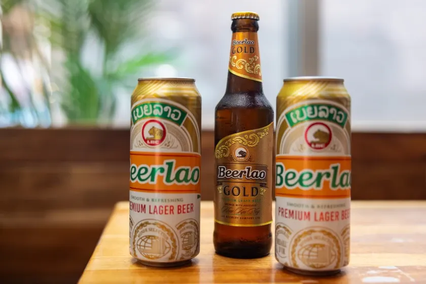 Cans and a bottle of Beerlao, Laos' national lager, on a wooden table in Vientiane
